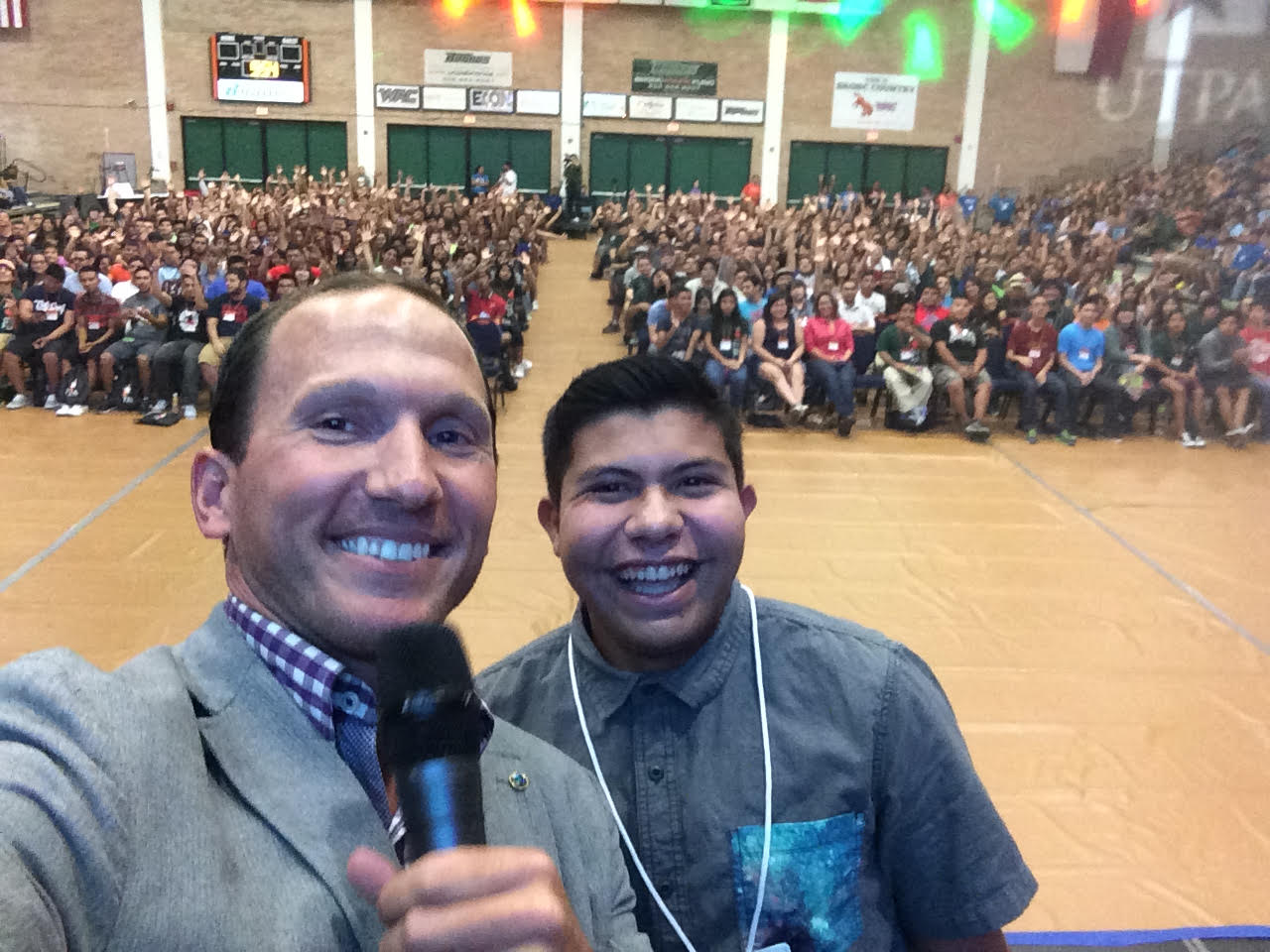 Kevin on stage with a student at a school assembly